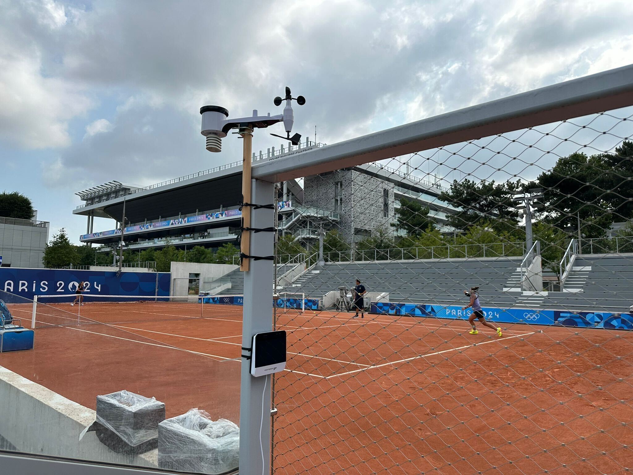 WeatherXM Pulse station installed on fence at Roland Garros tennis court during Paris 2024 Olympic match