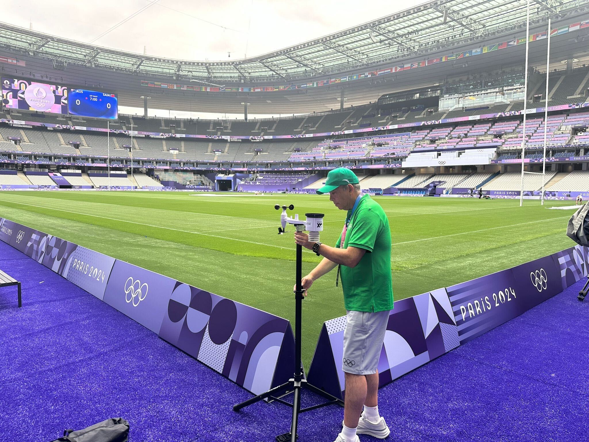 Olympic official deploying WeatherXM station on tripod at Stade de France during Paris 2024